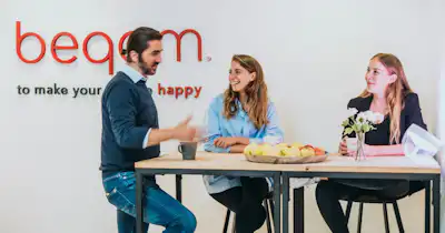 Male and female employees at beqom talking together