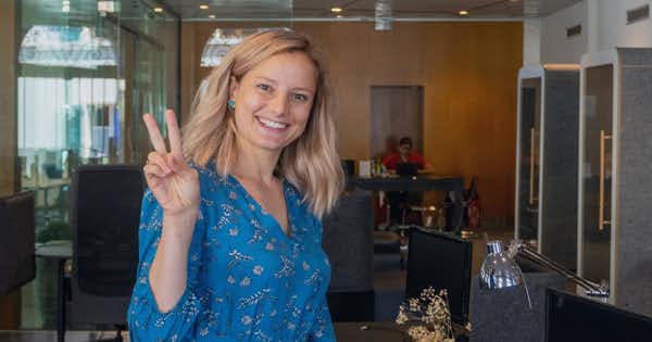 Femme souriante faisant le signe de paix avec deux doigts.