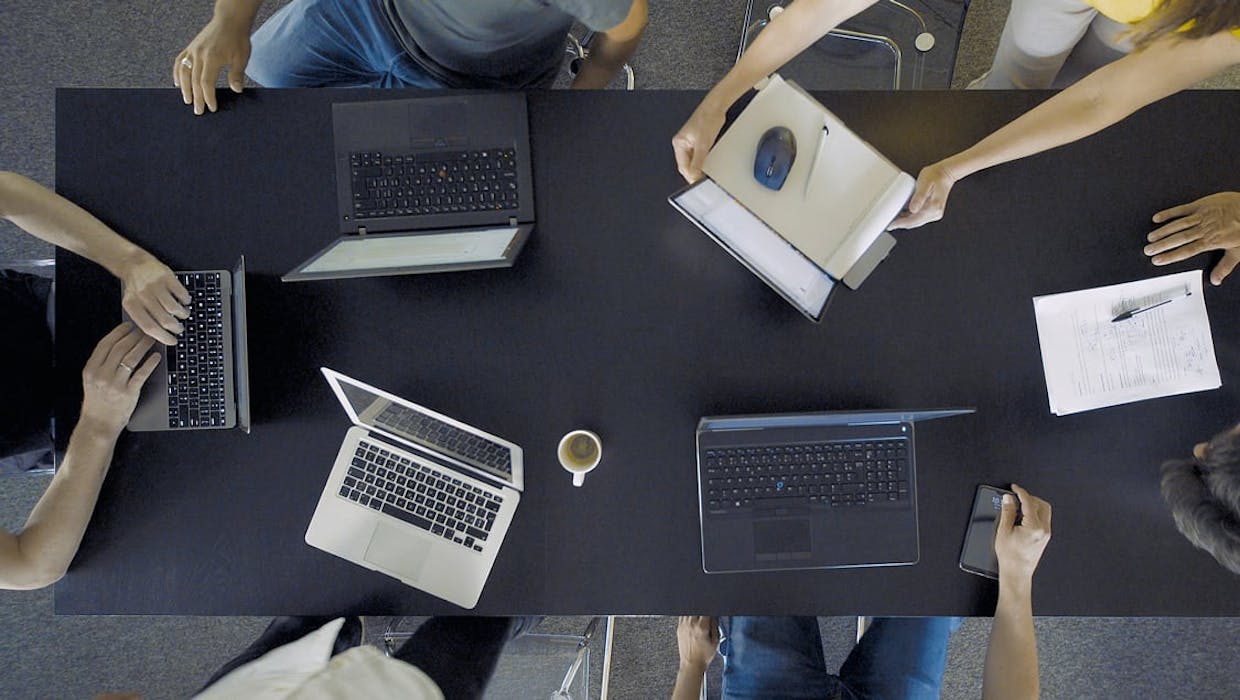 Des personnes réunies autour d'une table avec des ordinateurs portables.