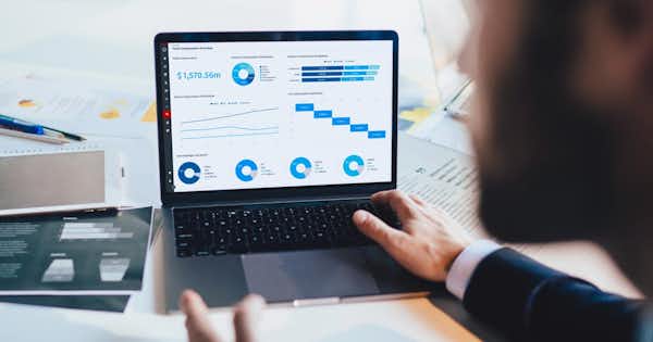 Écran d'ordinateur avec tableaux et graphiques, mains sur le clavier.
