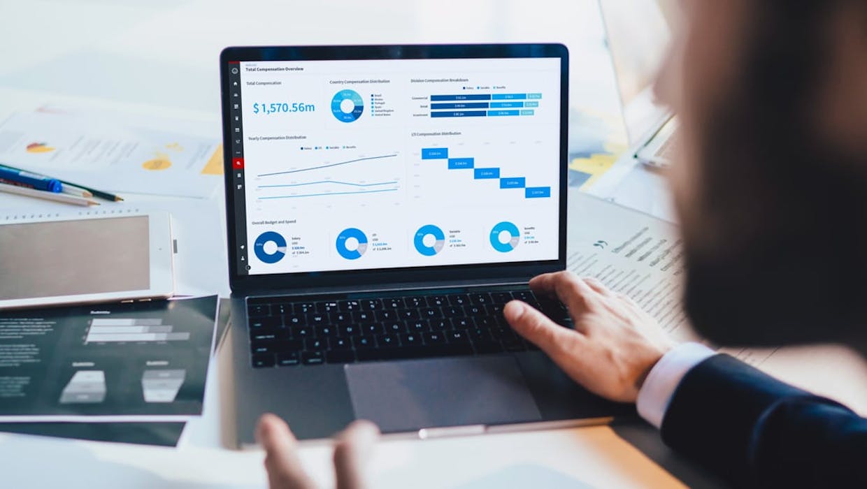 Écran d'ordinateur avec tableaux et graphiques, mains sur le clavier.