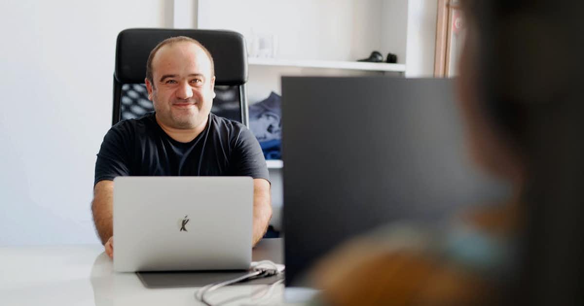 Two employees at desks facing each other.
