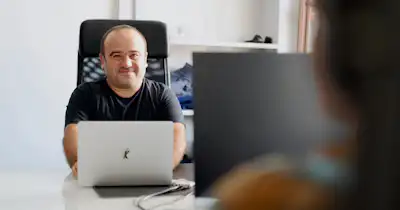 Two employees at desks facing each other.