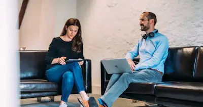 Deux personnes assises sur un canapé.