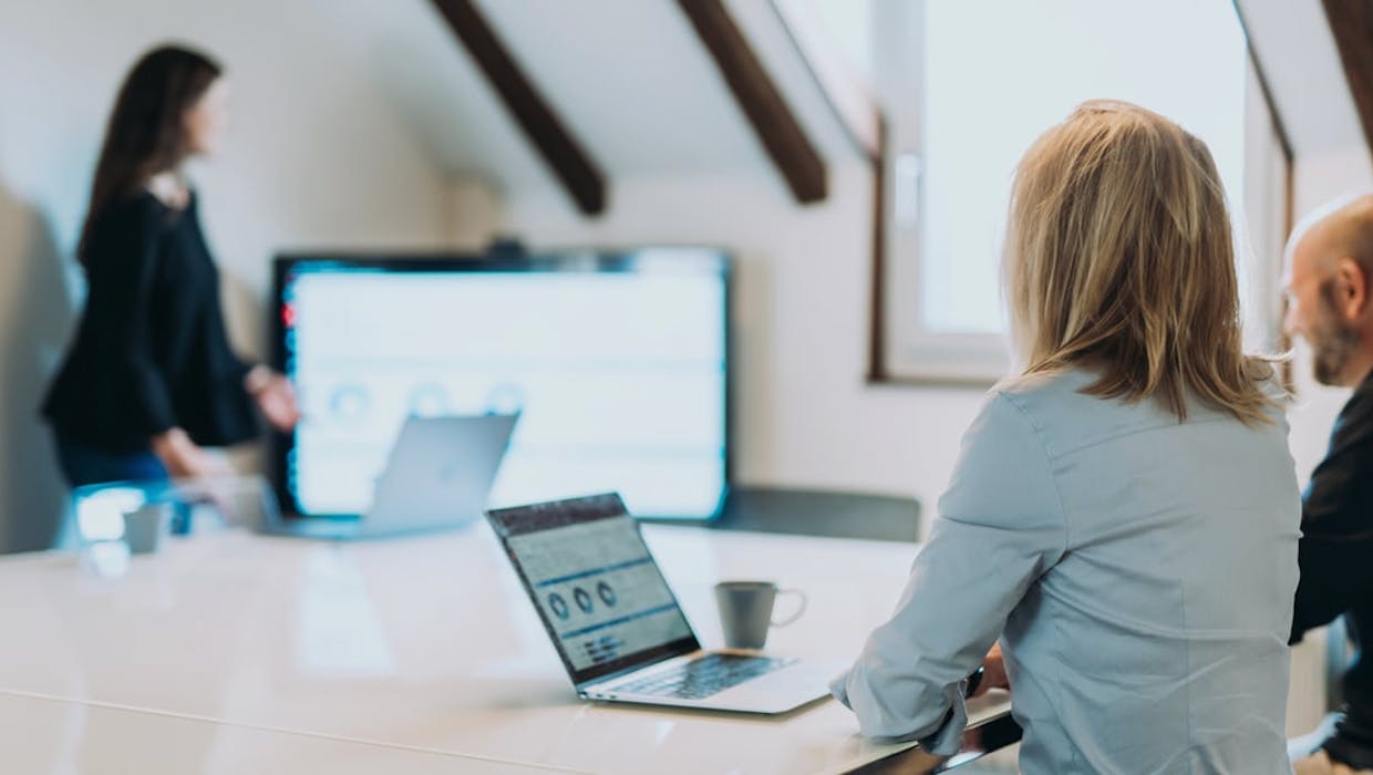 Femme présentant à d'autres personnes assises à une table.