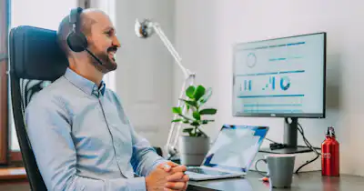 Homme assis devant un ordinateur avec un casque audio.