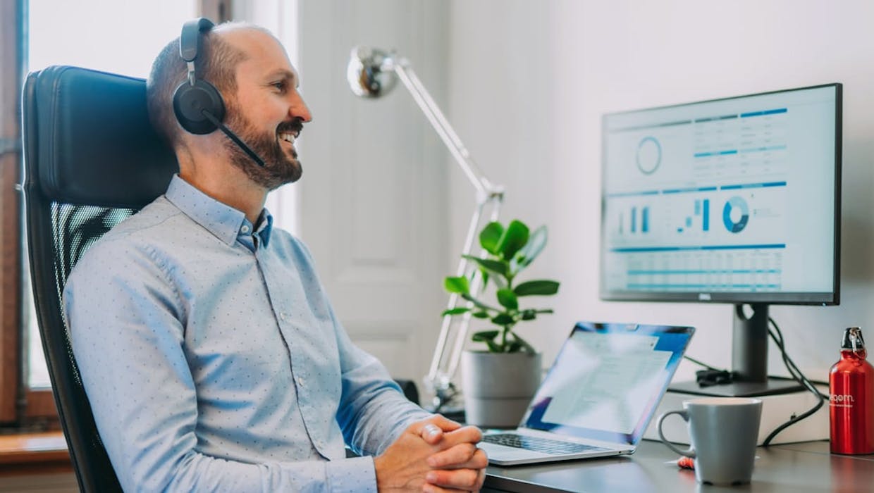 Homme assis devant un ordinateur avec un casque audio.