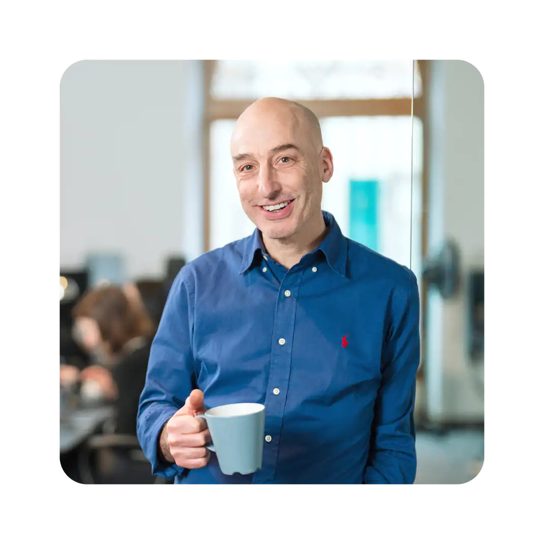 A man holding a coffee cup in an office.