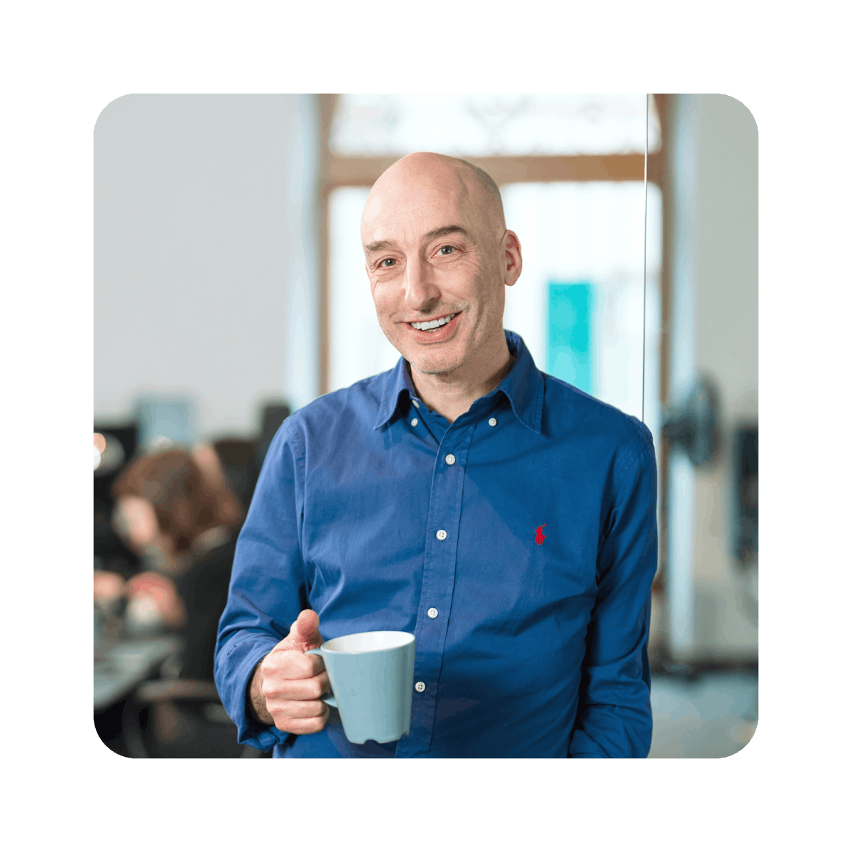 A man holding a coffee cup in an office.