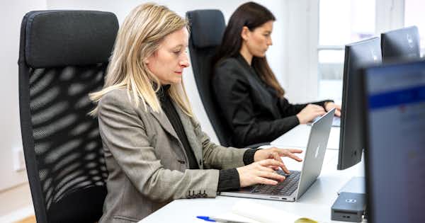 Two women in the office doing focused computer work.