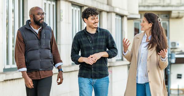 Three people talking in the street.