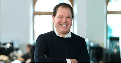Smiling man with arms folded.