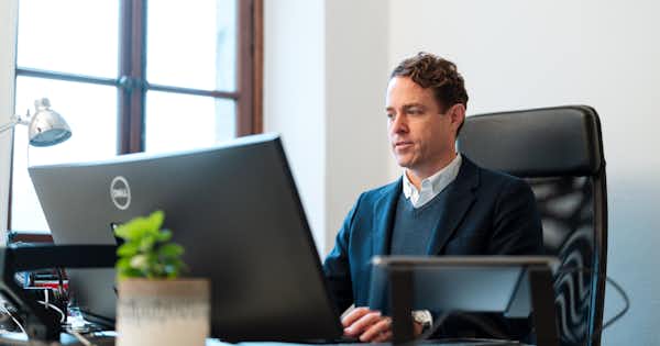 Homme assis à un bureau regardant son ordinateur.
