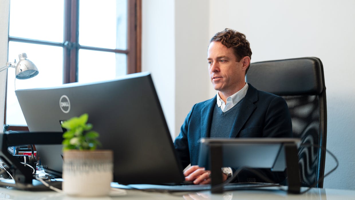 Homme assis à un bureau regardant son ordinateur.