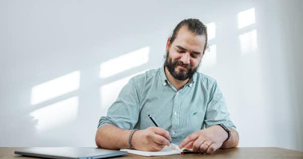 Man at desk writing in a notebook