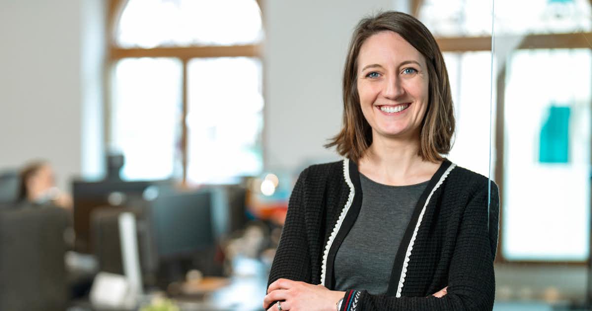 A woman facing the camera. Smiling in an office environment.
