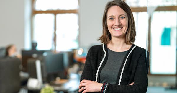 A woman facing the camera. Smiling in an office environment.