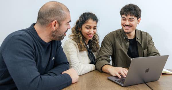 Three people sitting together at a desk.