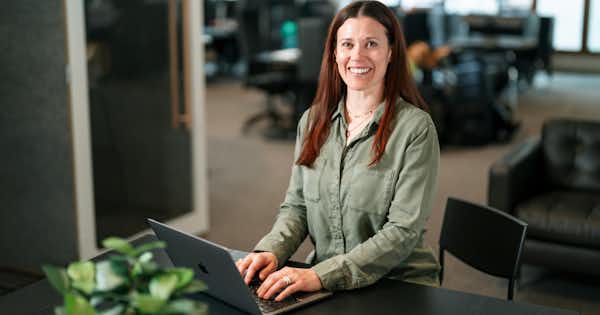 A woman sitting at a desk, workin on a laptop.