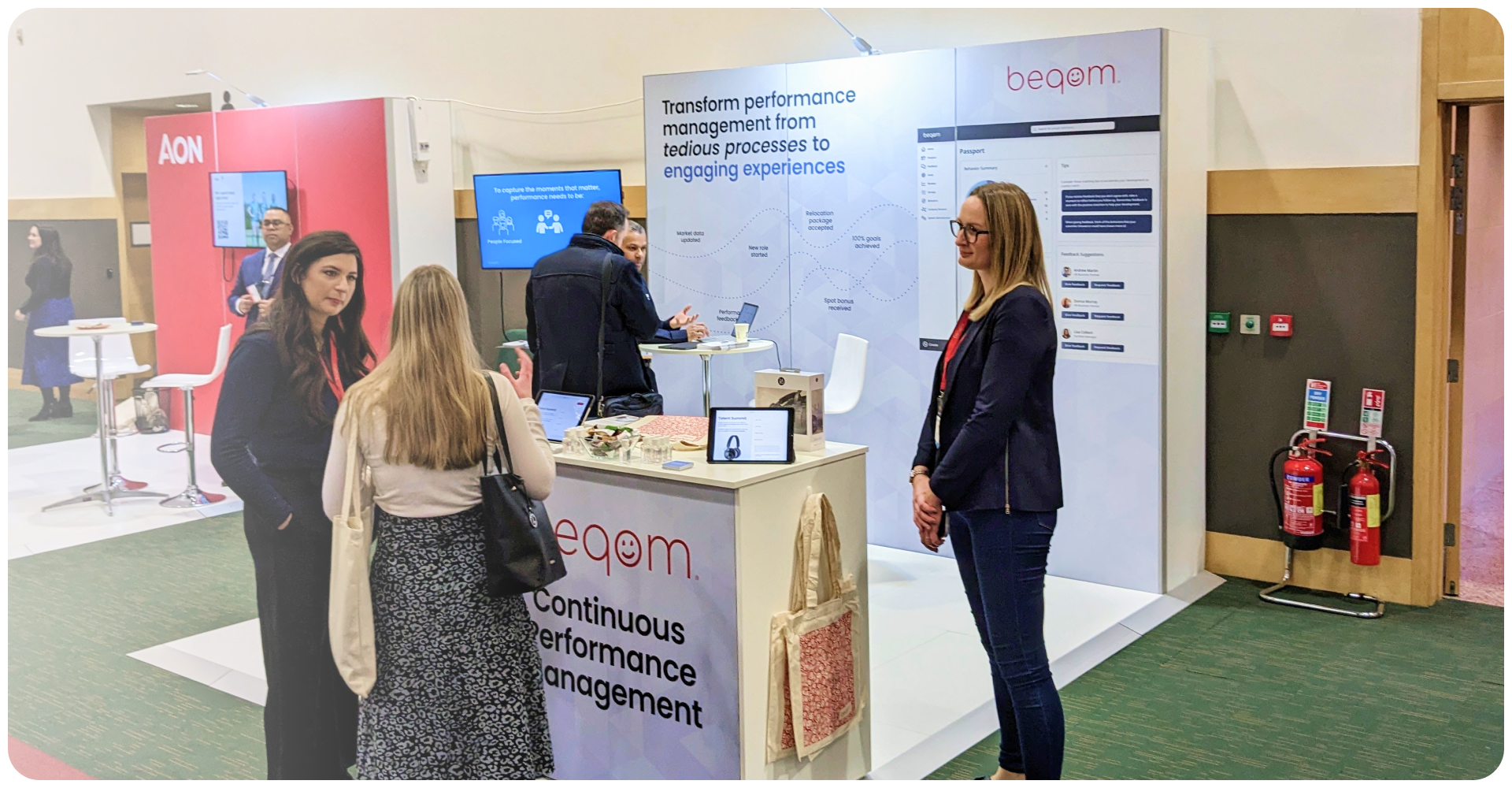 People talking at an event in front of beqom's booth