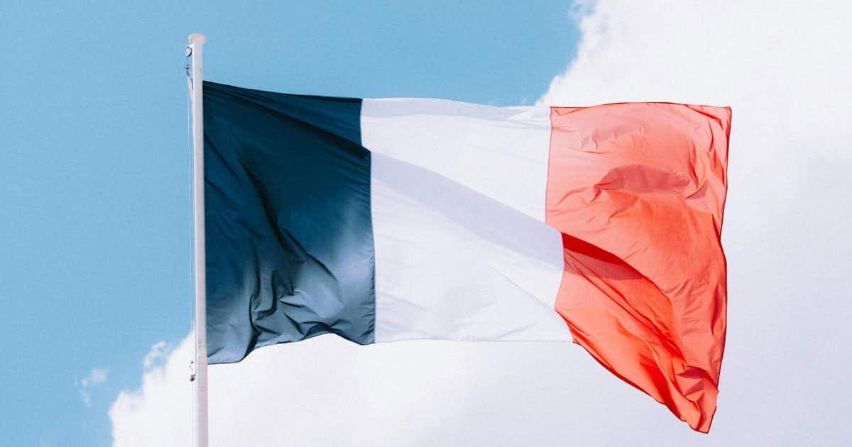 A photo of the French flag with a blue sky in the background.