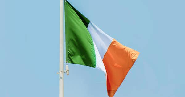 A photo of the Irish flag with a blue sky in the background.