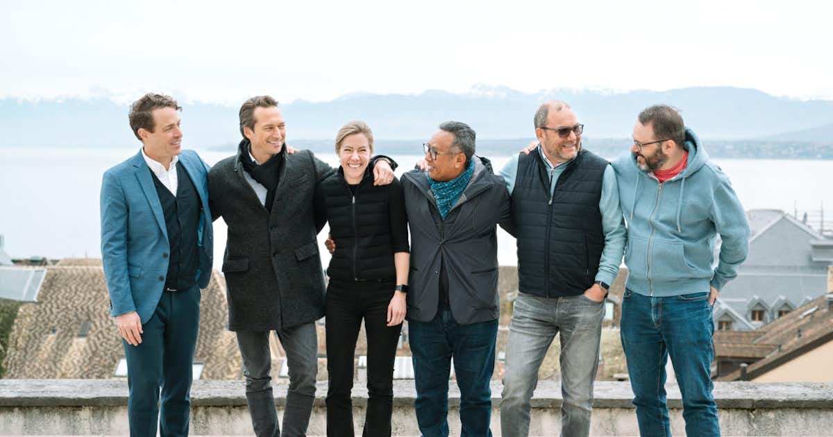 Groupe de personnes en plein air devant un lac.