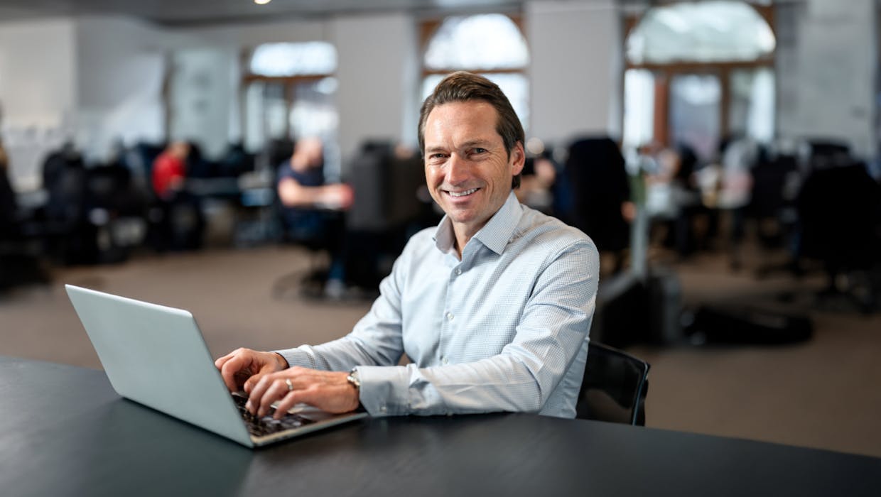 Homme assis à un bureau avec un ordinateur portable.