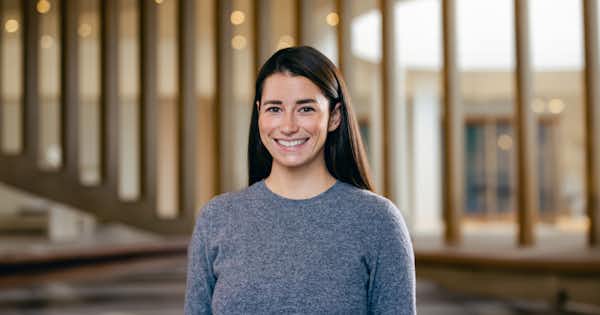 Femme debout dans un bureau, souriante.
