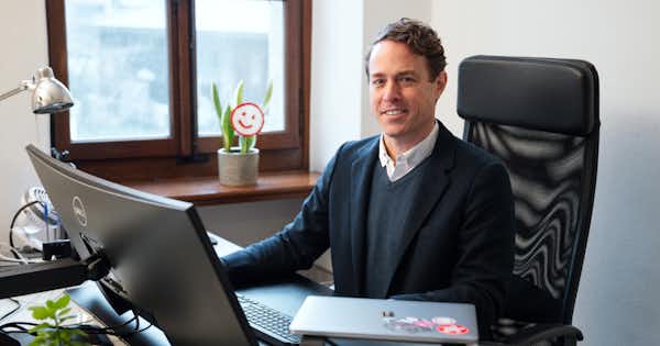 man sitting in office setting and smiling