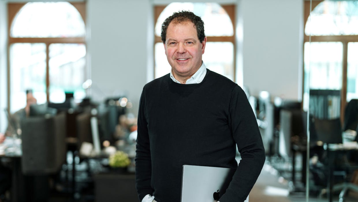 Homme dans un bureau avec un ordinateur portable sous le bras.
