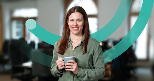Woman in an office holding a coffee cup.