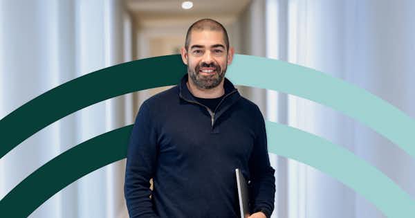 man smiling, with computer on his hand, at the office