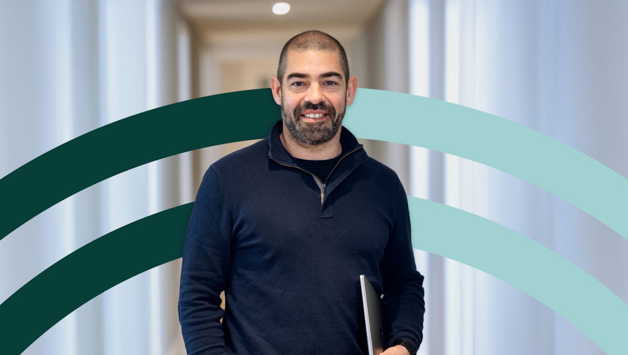 man smiling, with computer on his hand, at the office