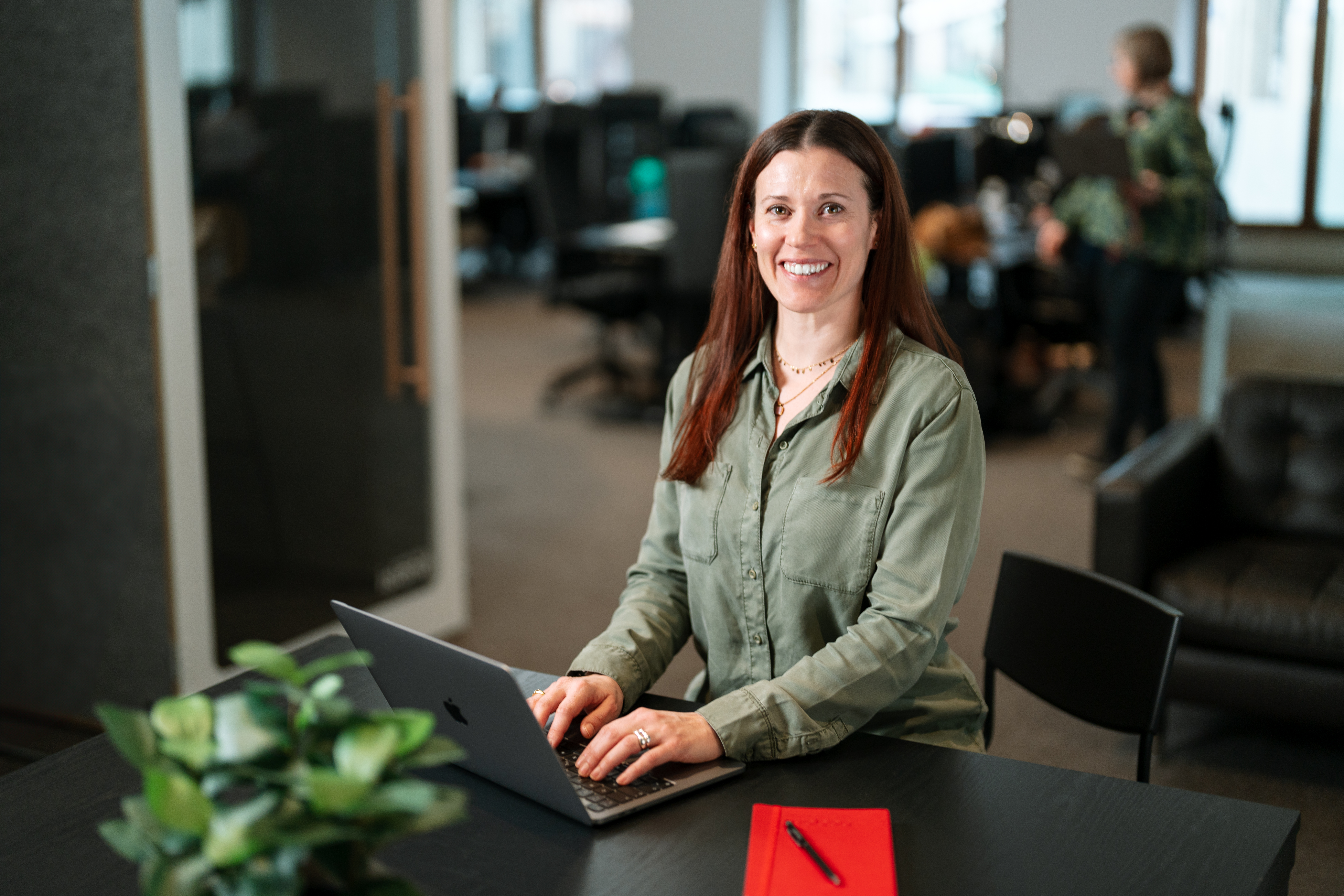 woman in an office setting smilling to the camera.