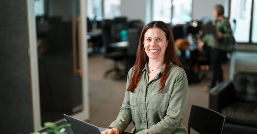 woman in an office setting smilling to the camera.