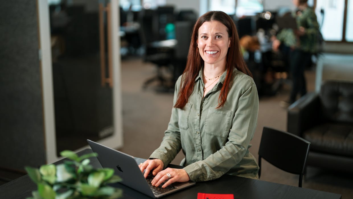 woman in an office setting smilling to the camera.