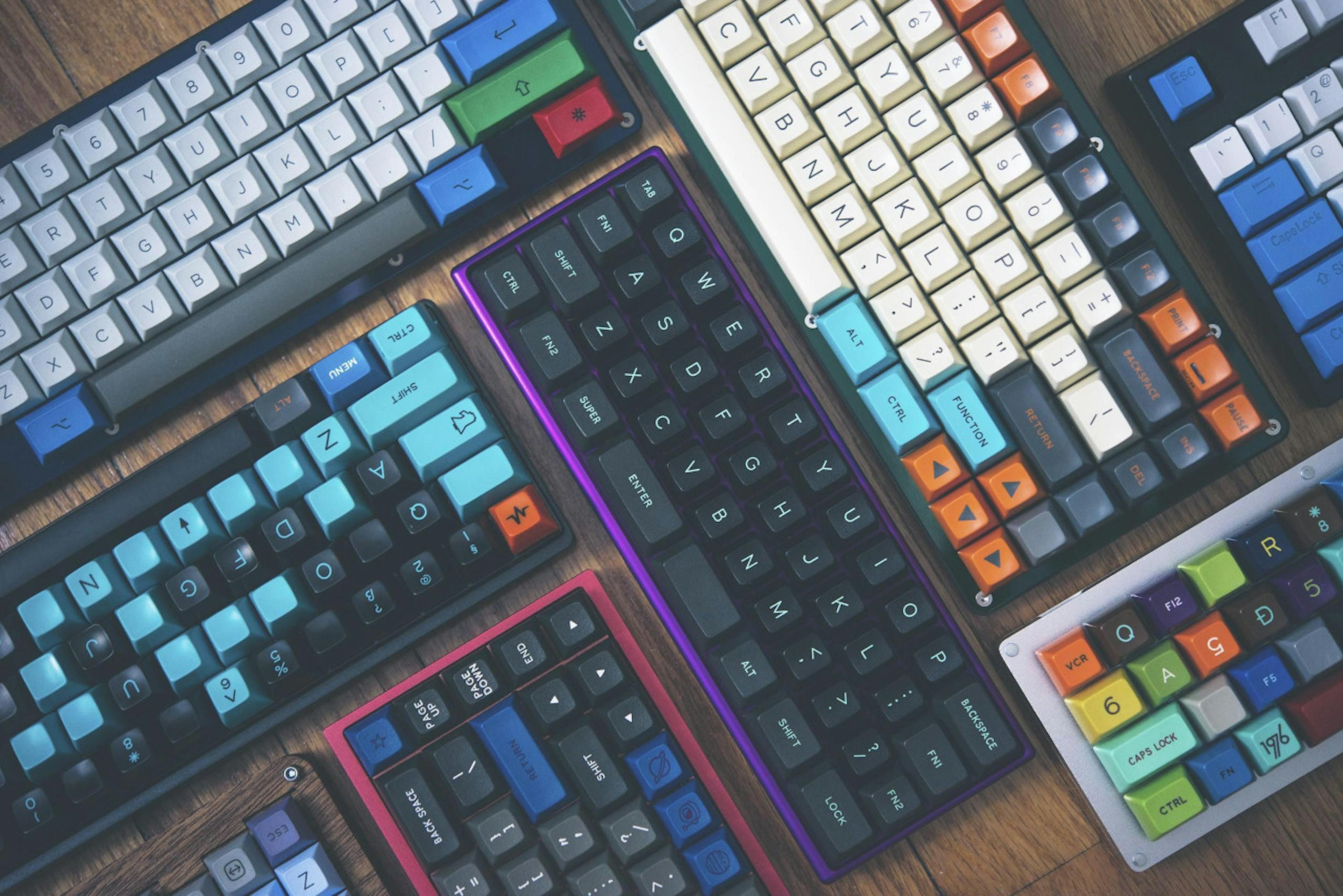 Diversos teclados gamer sobre uma mesa