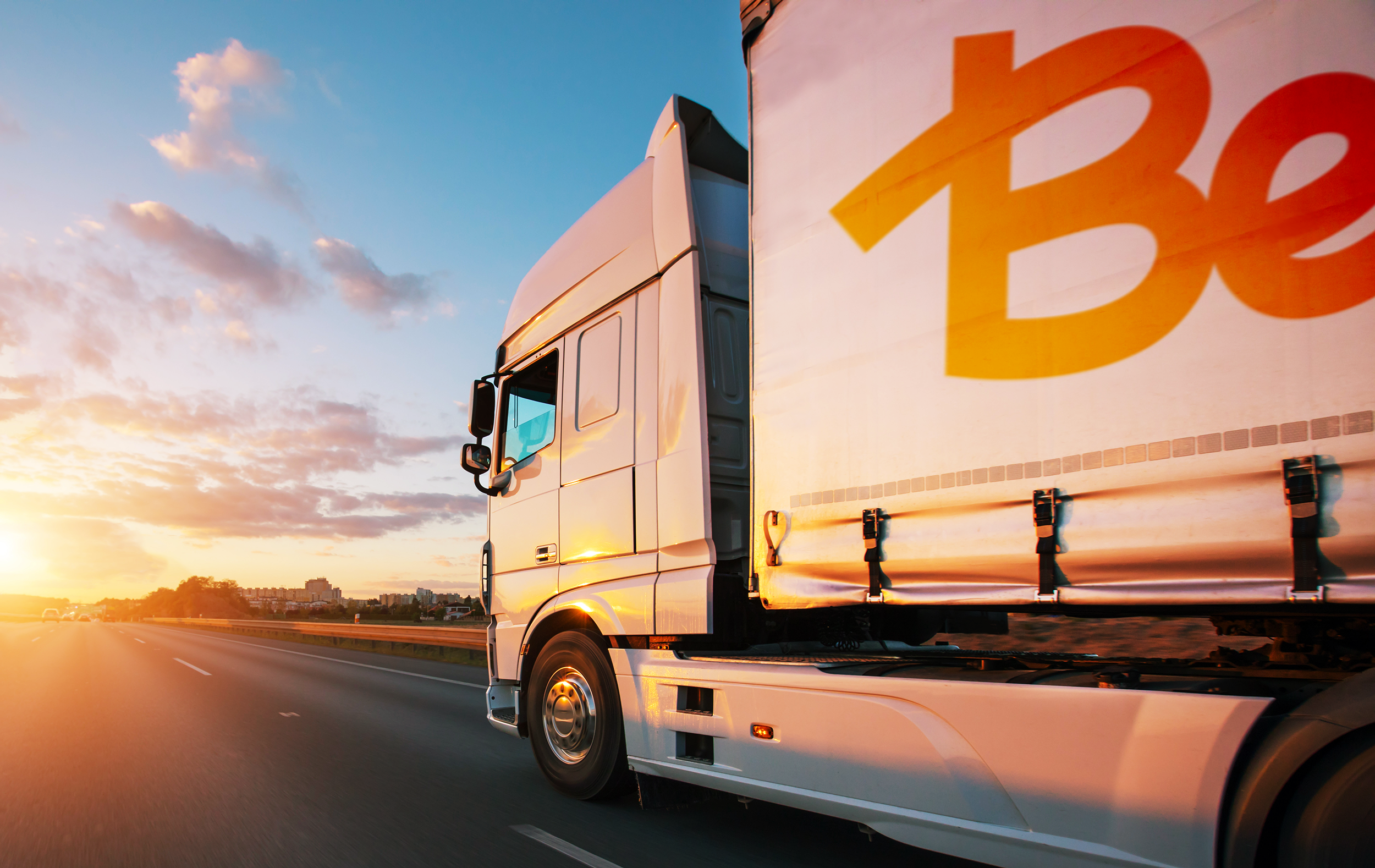 Lastbil från Best på vägen, i solnedgång.