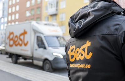 Rygg på Best-medarbetare med synlig logotyp, budbil i bakgrunden.