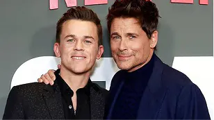 Rob Lowe posing with a younger man at an event, both smiling
