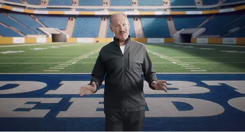 Bill Cowher standing on a football field in an empty stadium