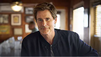 Rob Lowe in a dark jacket in a wood-paneled restaurant