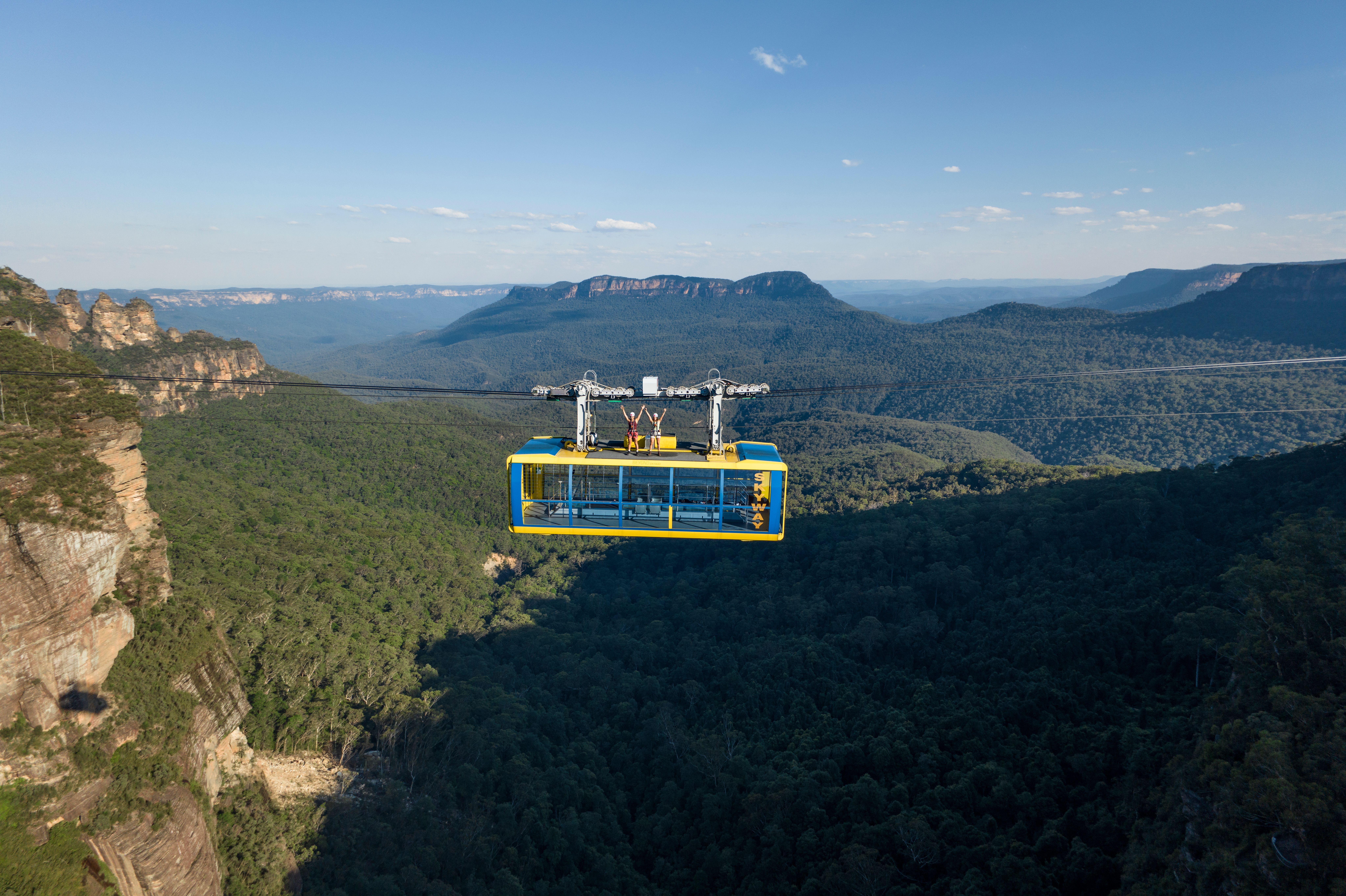 Two women on top of the Scenic Skyway for the Beyond Skyway experience with the Three Sisters in the background