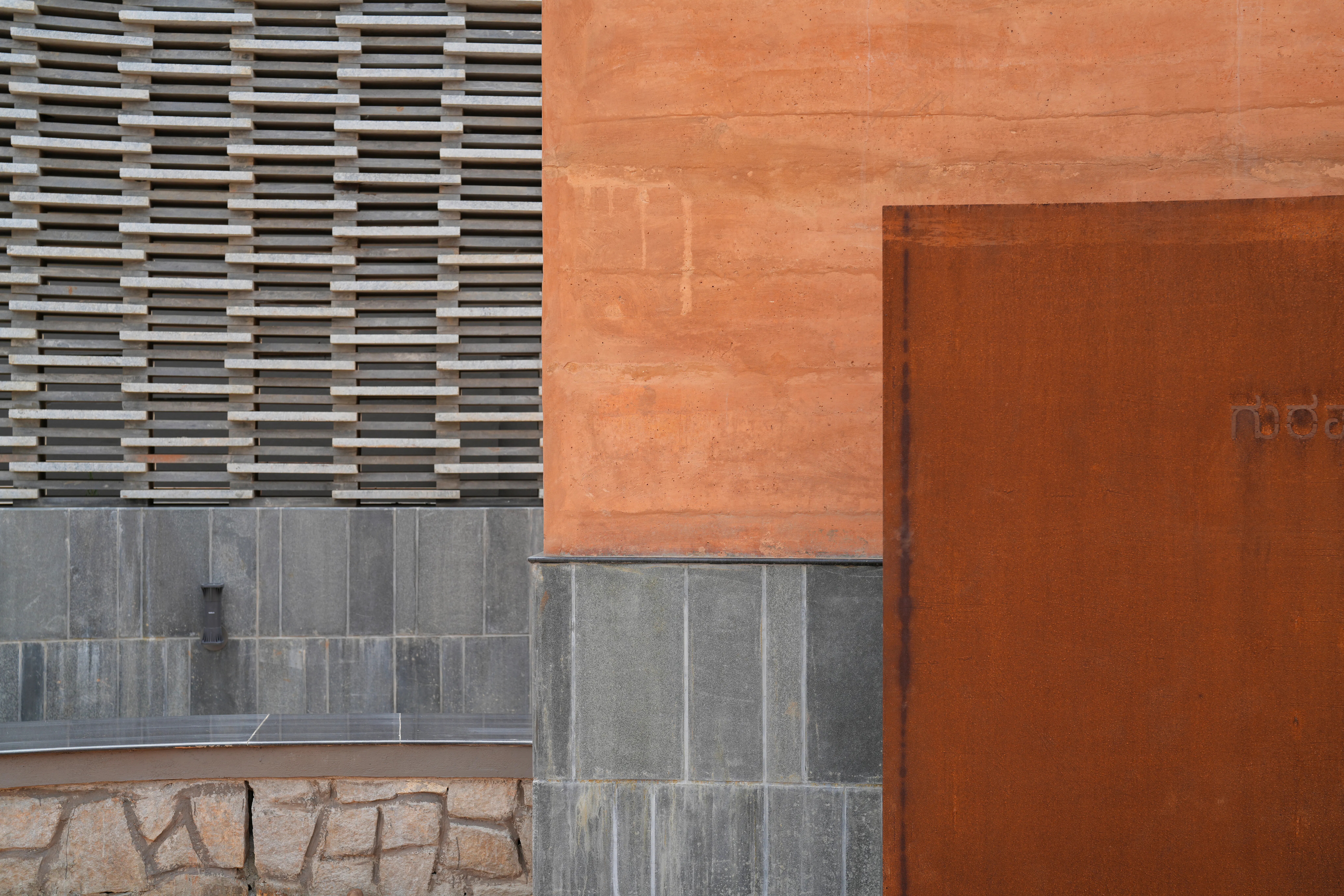STONE JAALI, RAMMED EARTH WALL & CORTEN STEEL SIGNAGE