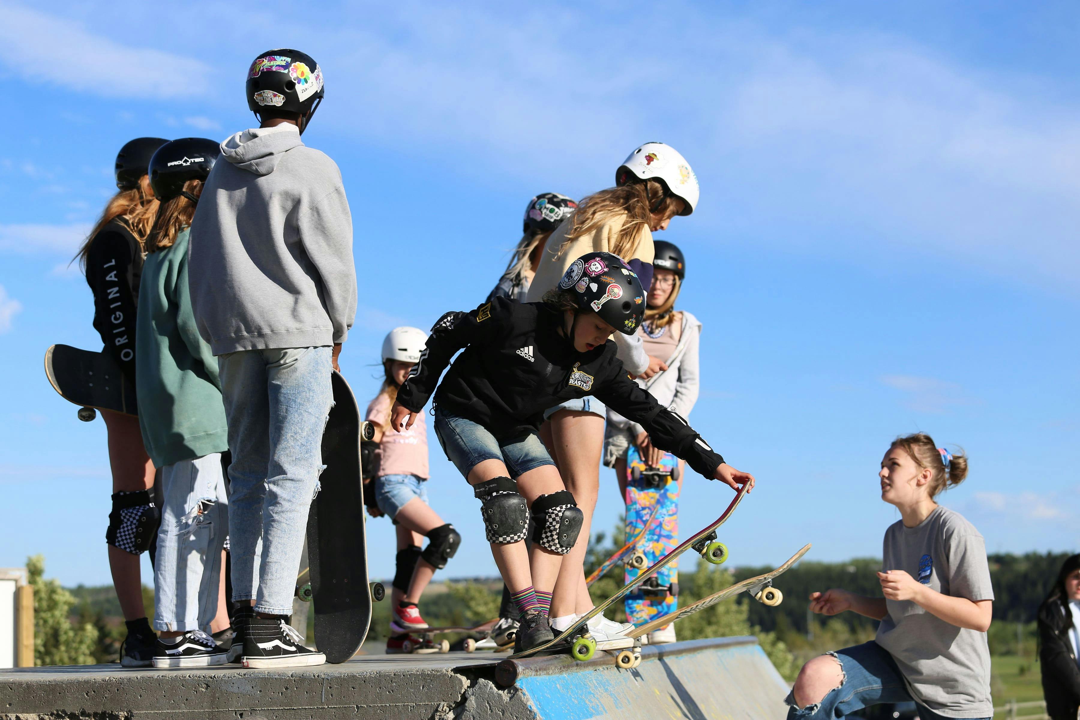 A volunteer helping girls learn to drop into the quarter pipe.