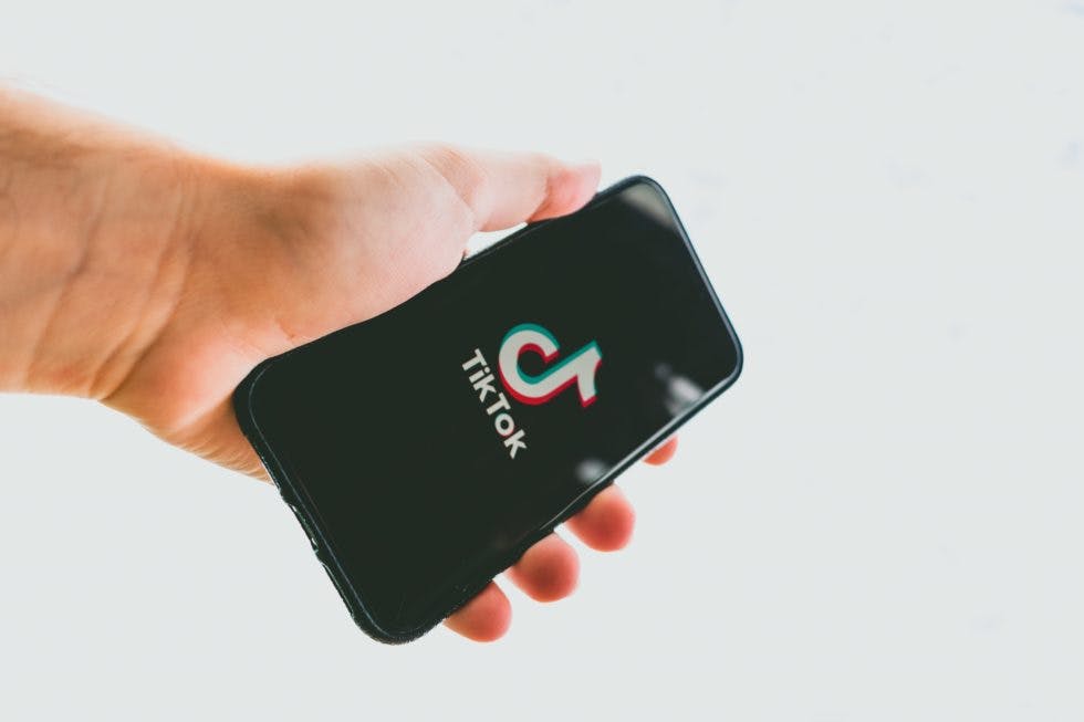 A guy holding a phone displaying tiktok landing page
