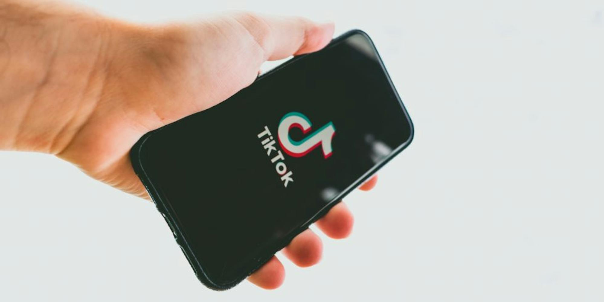 A guy holding a phone displaying tiktok landing page