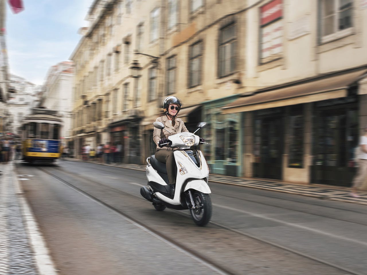 Yamaha D'elight 125 scooter in Milky White riding down city street