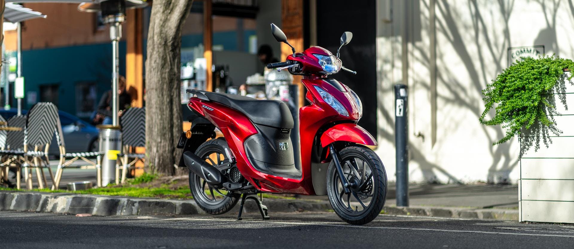 Honda NSC110 Dio in candy red, parked.